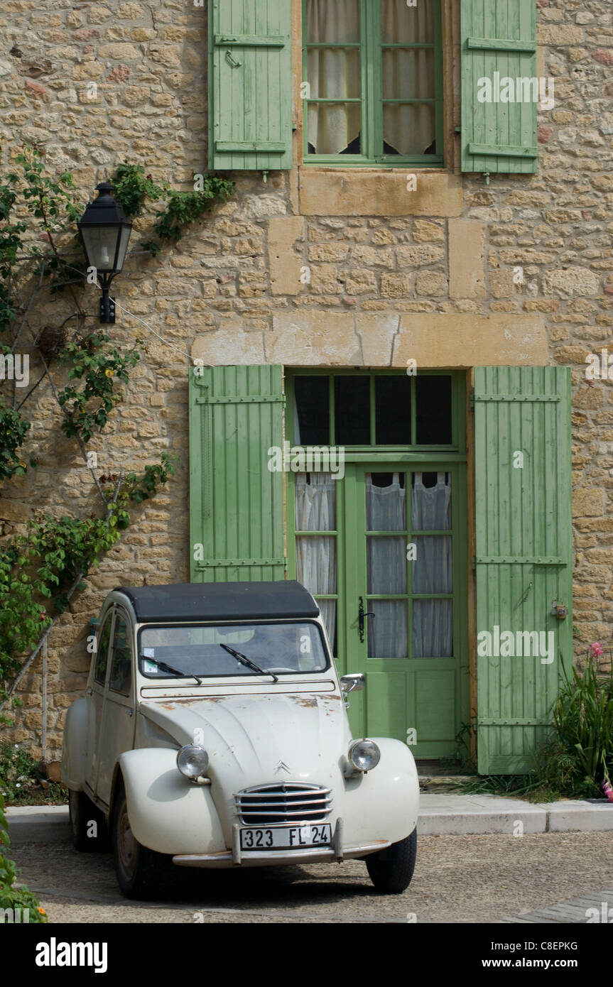 An old Deux Chevaux car parked in front of an old village house, Dordogne, France Stock Photo