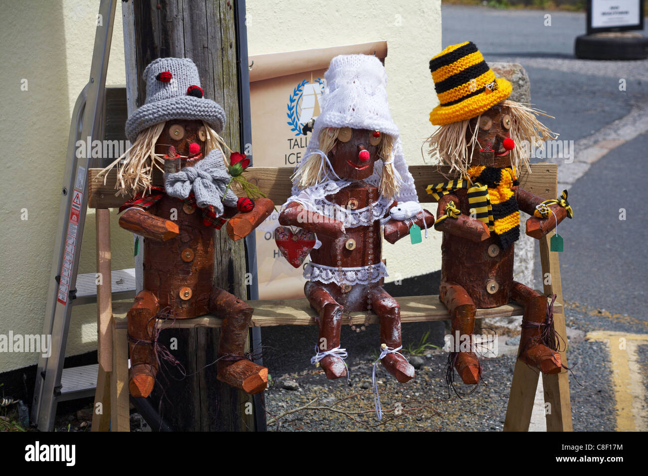 Wooden carved characters dressed up, sat on bench outside shop in Charlestown, Cornwall Stock Photo