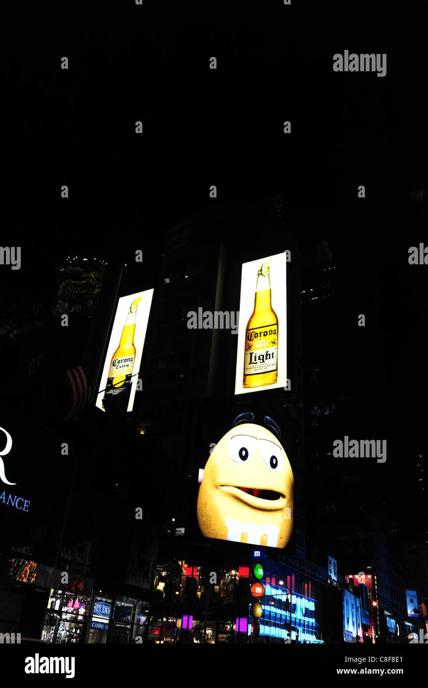 Night-time large yellow neon M&M image, black eyes mouth open, front M&M World candy store, 7th Avenue, Times Square, New York Stock Photo