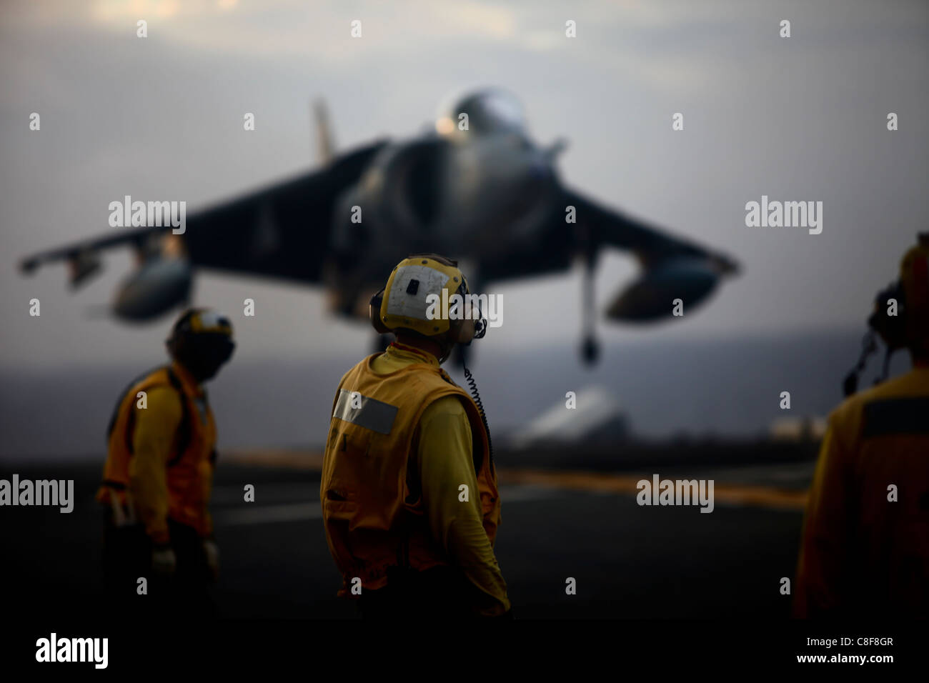 U.S. Navy Boatswains Mates observes a U.S. Marine AV-8B Harrier  landing aboard the flight deck of USS Essex Stock Photo