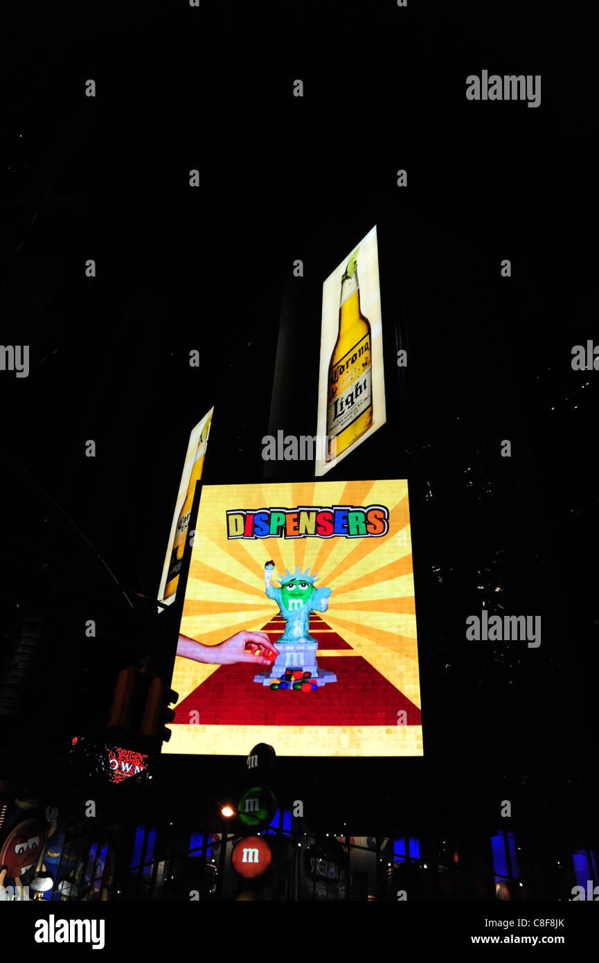 Night shot rising sun neon screen image advertising M&M Dispensers, M&M World candy store, 7th Avenue, Times Square, New York Stock Photo