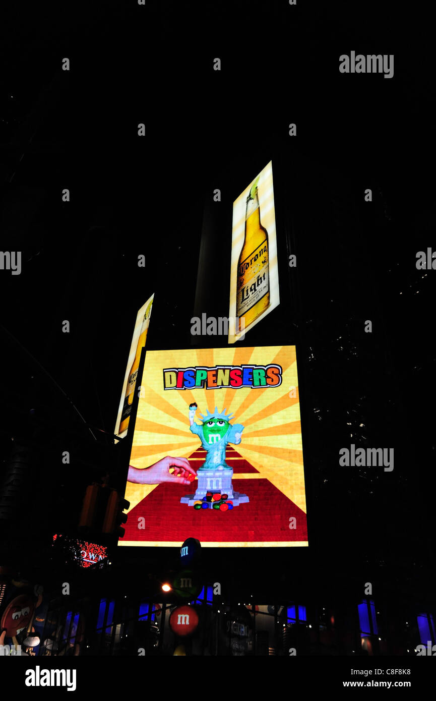 Night shot large neon screen advertising M&M sweet dispensers, fron M&M World candy store, 7th Avenue, Times Square, New York Stock Photo