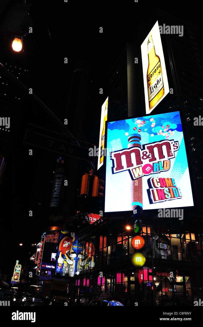 Night shot large neon screen advertising 'M&Ms World come inside' candy store, 7th Avenue/Broadway, Times Square, New York Stock Photo
