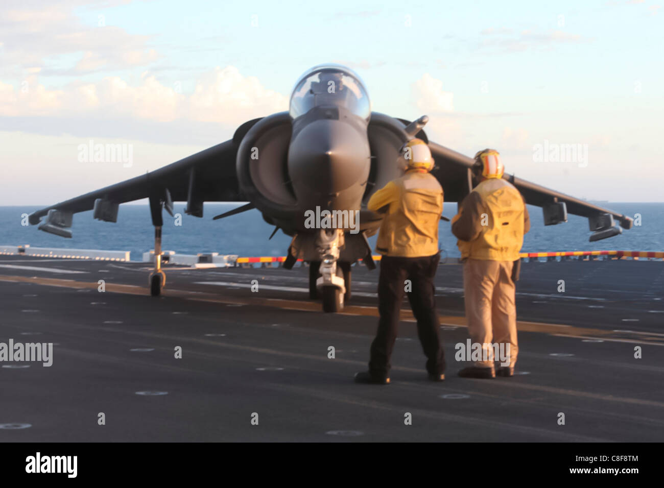 Navy flight deck crewmen direct an AV-8B Harrier jet on the flight deck of the USS Bonhomme Richard, Stock Photo