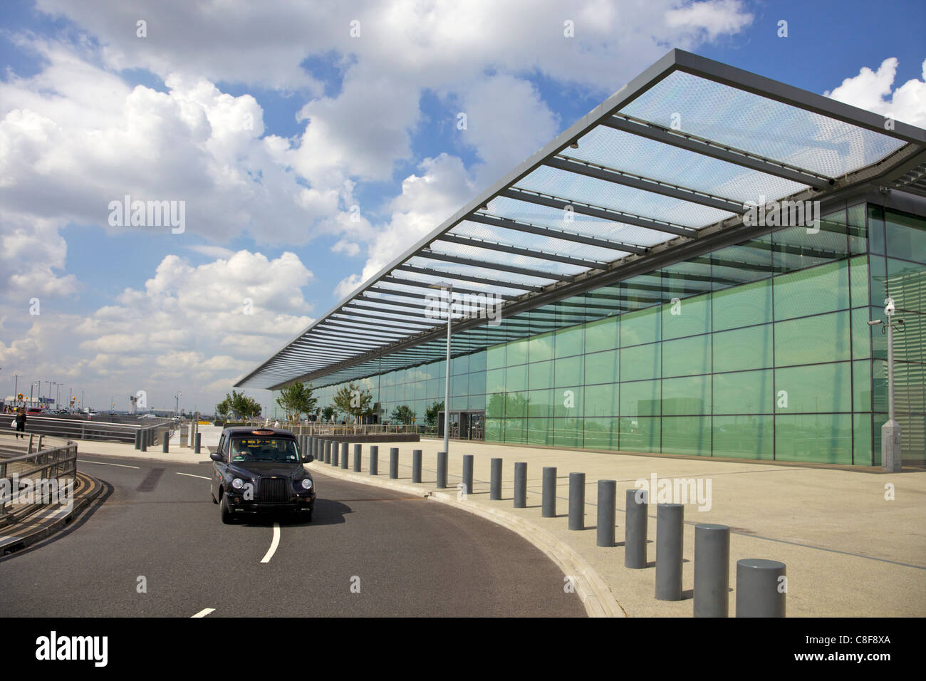 Black taxi cab drives away from Terminal 4, Heathrow Airport, London, England, United Kingdom Stock Photo