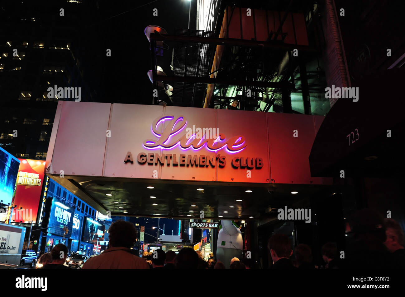 Night-time shot traffic, blue billboards, people walking under purple neon canopy Lace Gentlemen's Club, 7th Avenue, New York Stock Photo