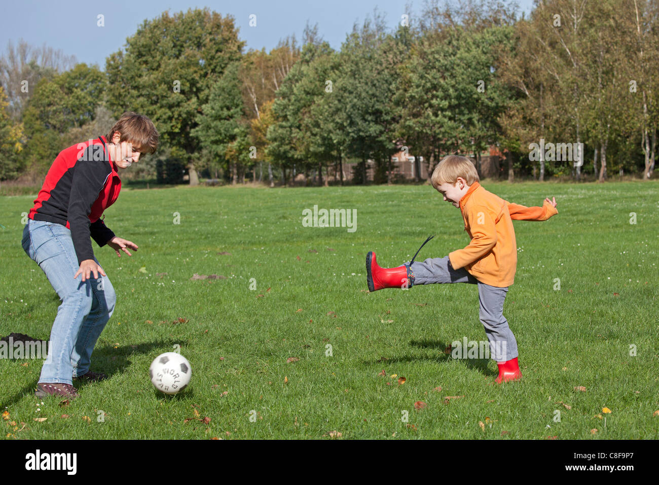 young boy playing football against a woman Stock Photo
