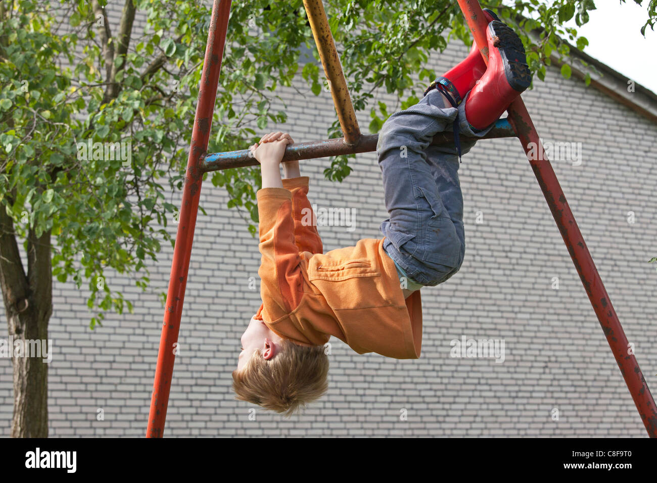 young boy hanging off monkey bars Stock Photo Alamy