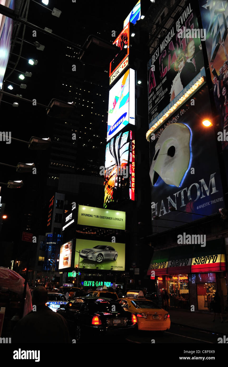 Night portrait traffic queue, taxis police car, below theatre billboards and neon advertisements, West 47th Street, New York Stock Photo