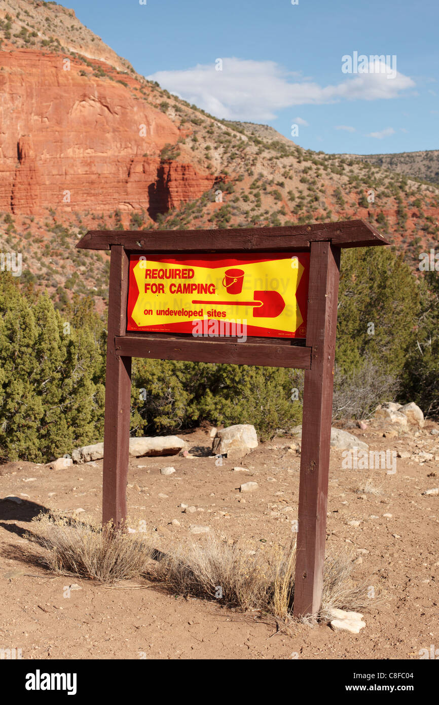 A sign in National Forest area of rural New Mexico indicating shovel and bucket required for camping. Stock Photo
