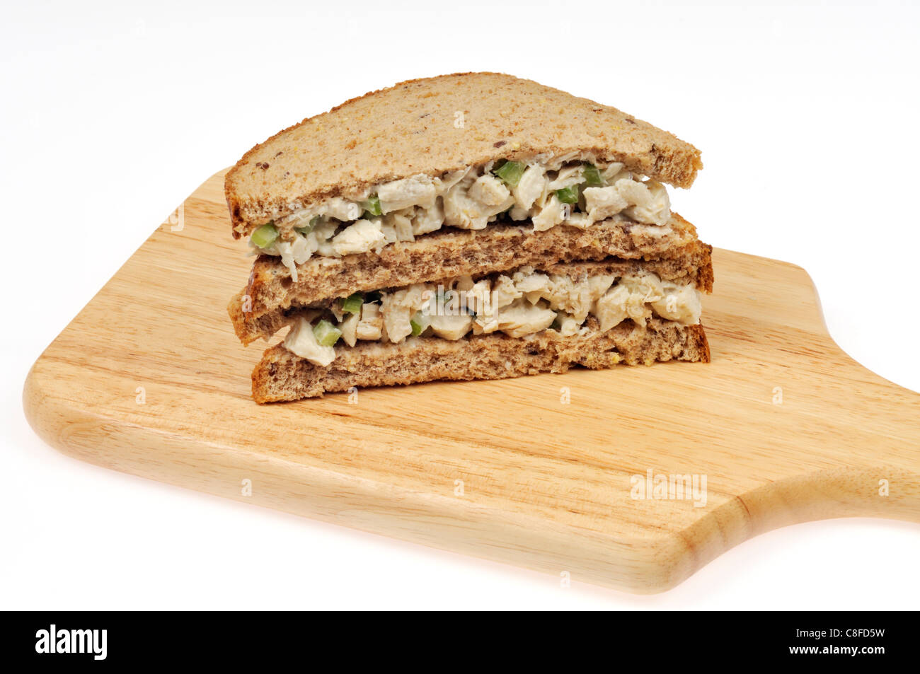 Chicken salad sandwich on wholemeal bread stacked on wood cutting board on white background. Stock Photo