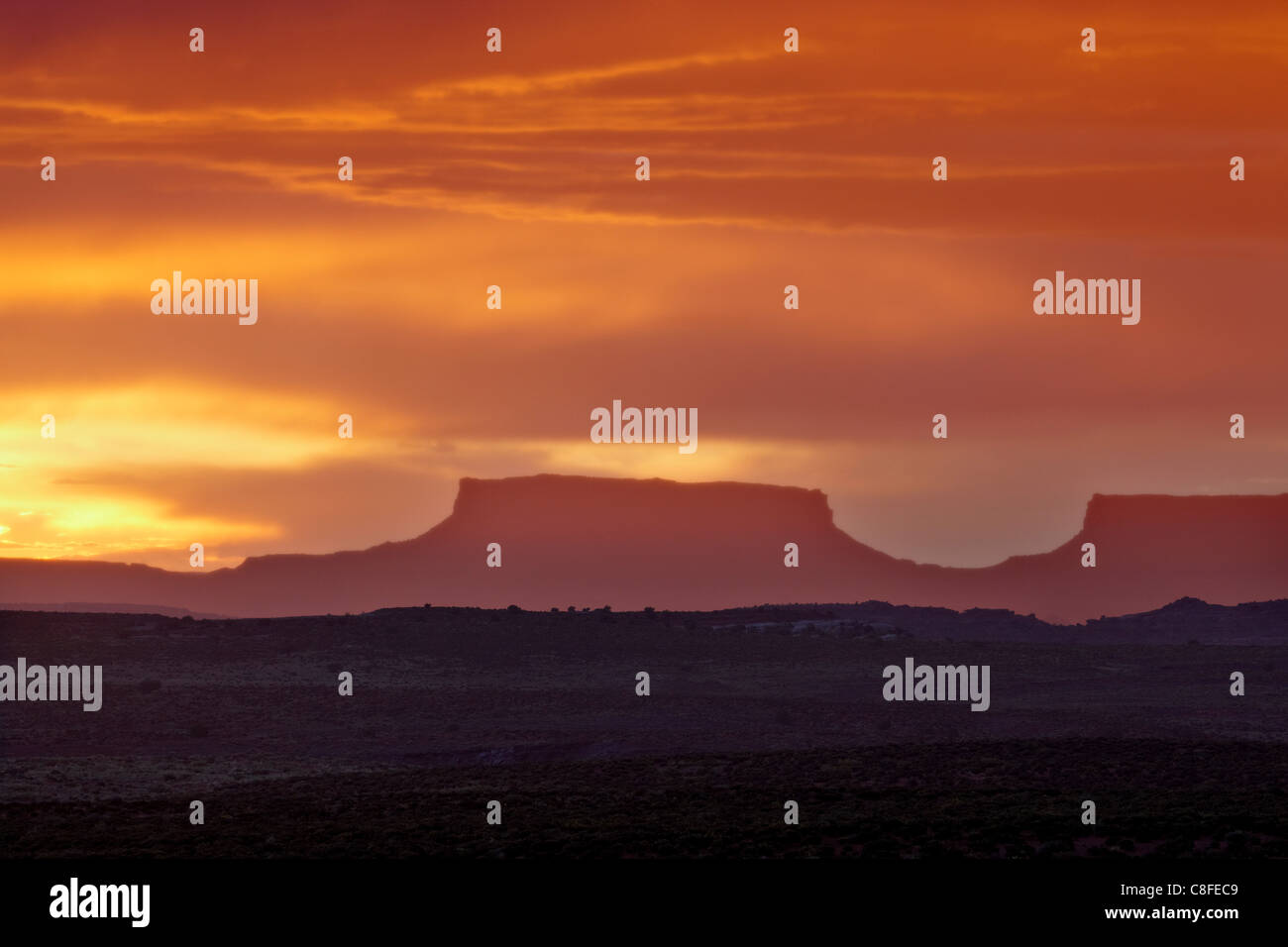 Orange clouds behind a butte at sunset, Canyon Country, Utah, United States of America Stock Photo