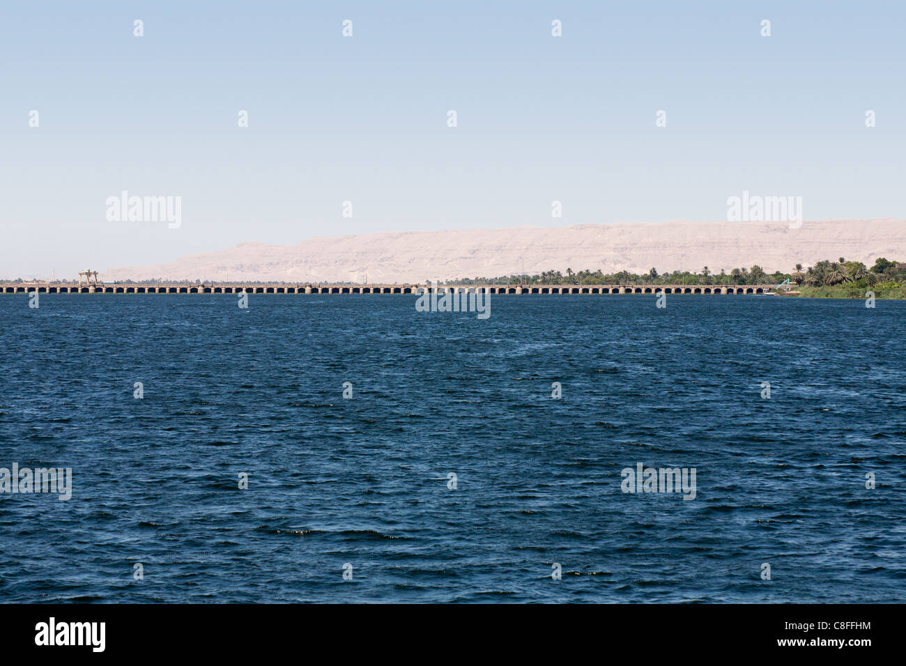 The Nile river in foreground with Esna barrage on the horizon and very distant desert mountain range behind, Egypt, Africa Stock Photo