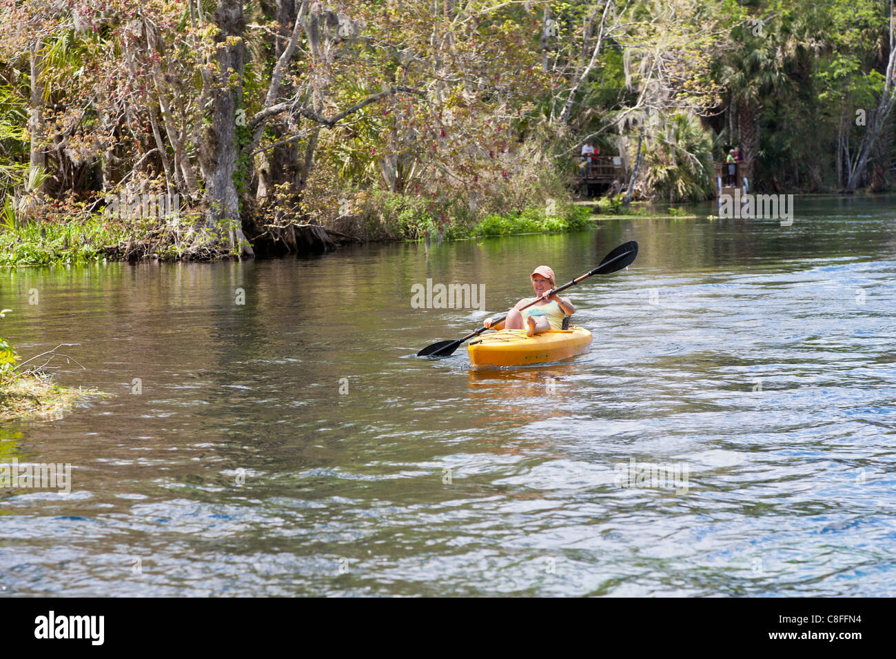 Young woman kayaking in orange kayak on Silver River near Silver Springs Attractions in Ocala Florida Stock Photo