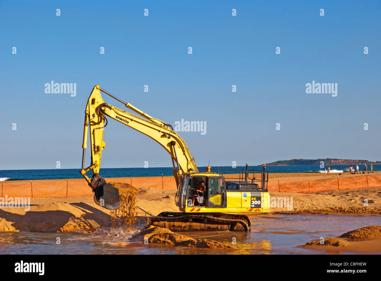 Tracked excavator working dredging sand from beach lagoon Stock Photo