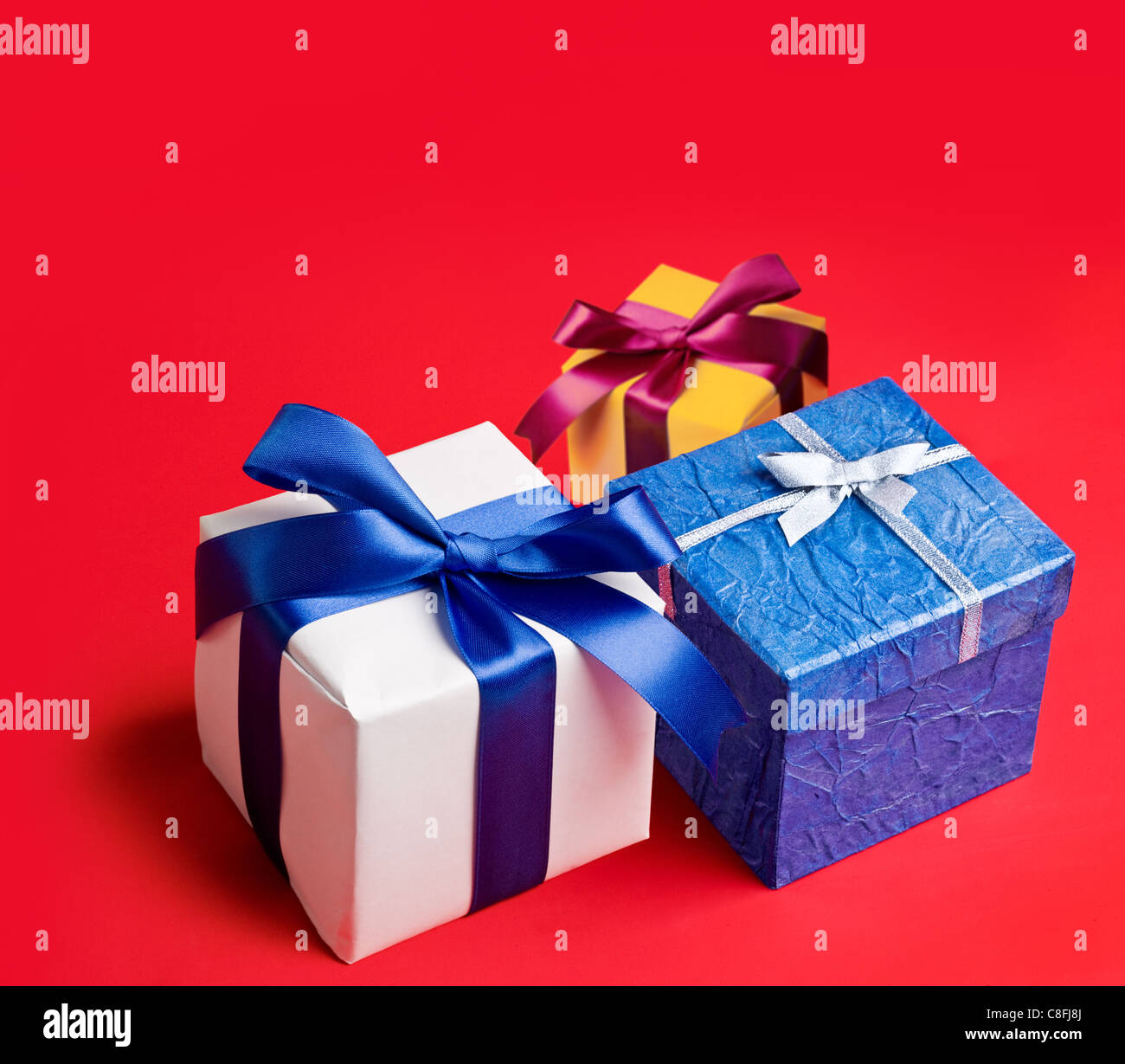 Three boxes with gifts on red background. Stock Photo