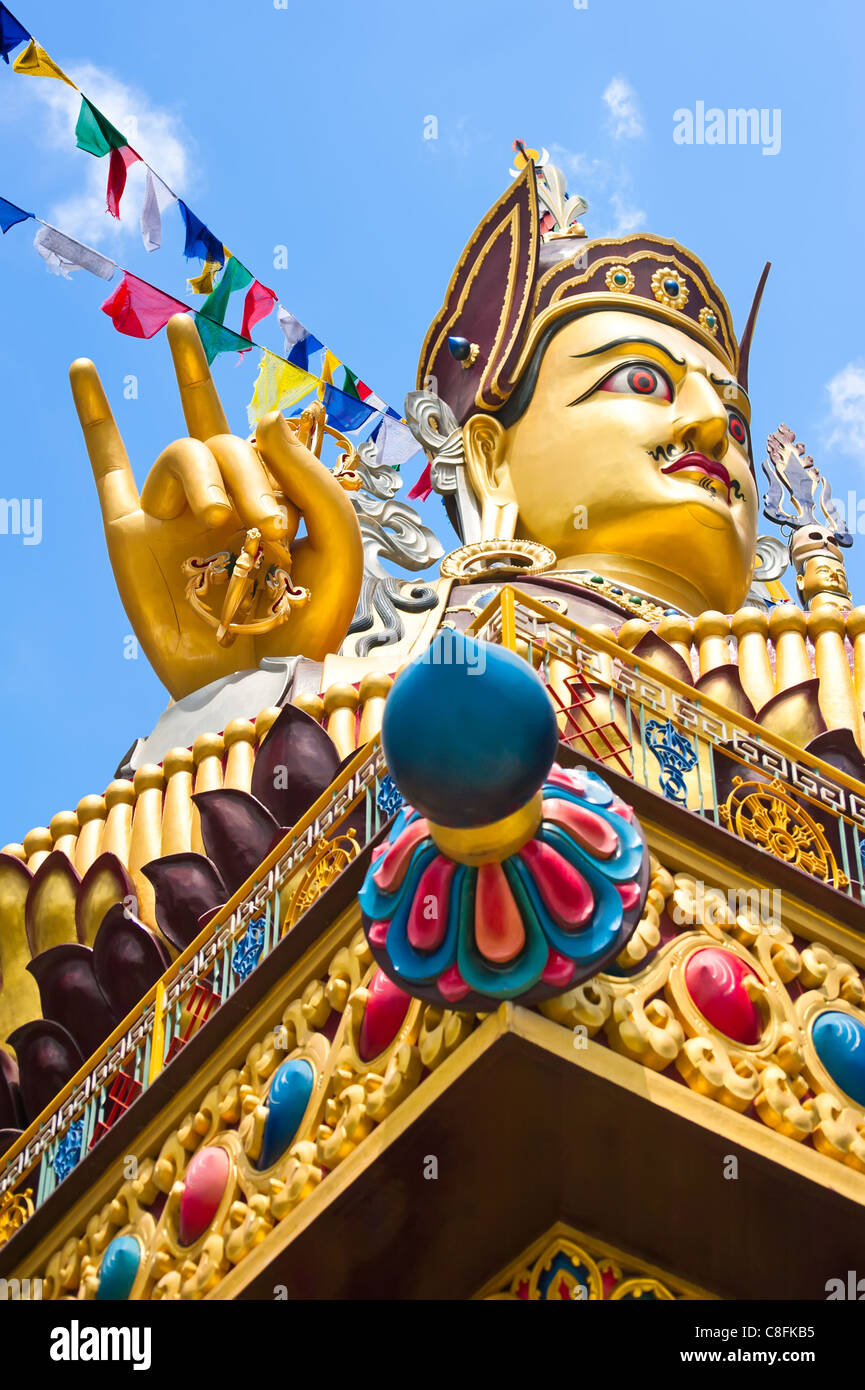 Golden Buddha sculpture in Tibetan monastery over blue sky with praying flags. Focus on hand Stock Photo