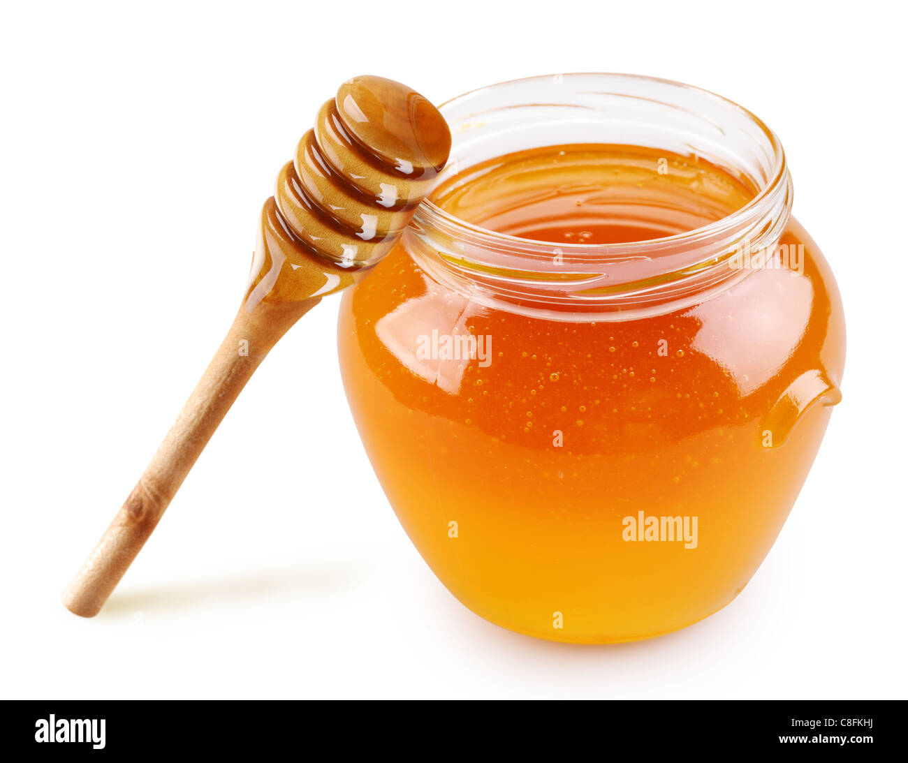 Honey in a glass jar with a stick on a white background. Stock Photo