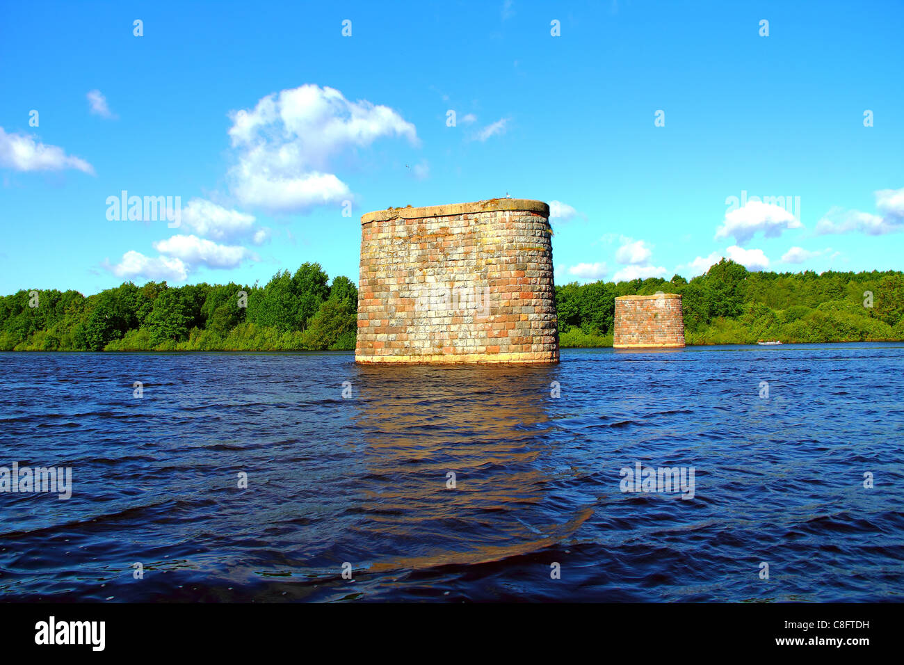 Summer landscape reflection of clouds in the river and forest shore. View of stone pillar of the old bridge. Stock Photo