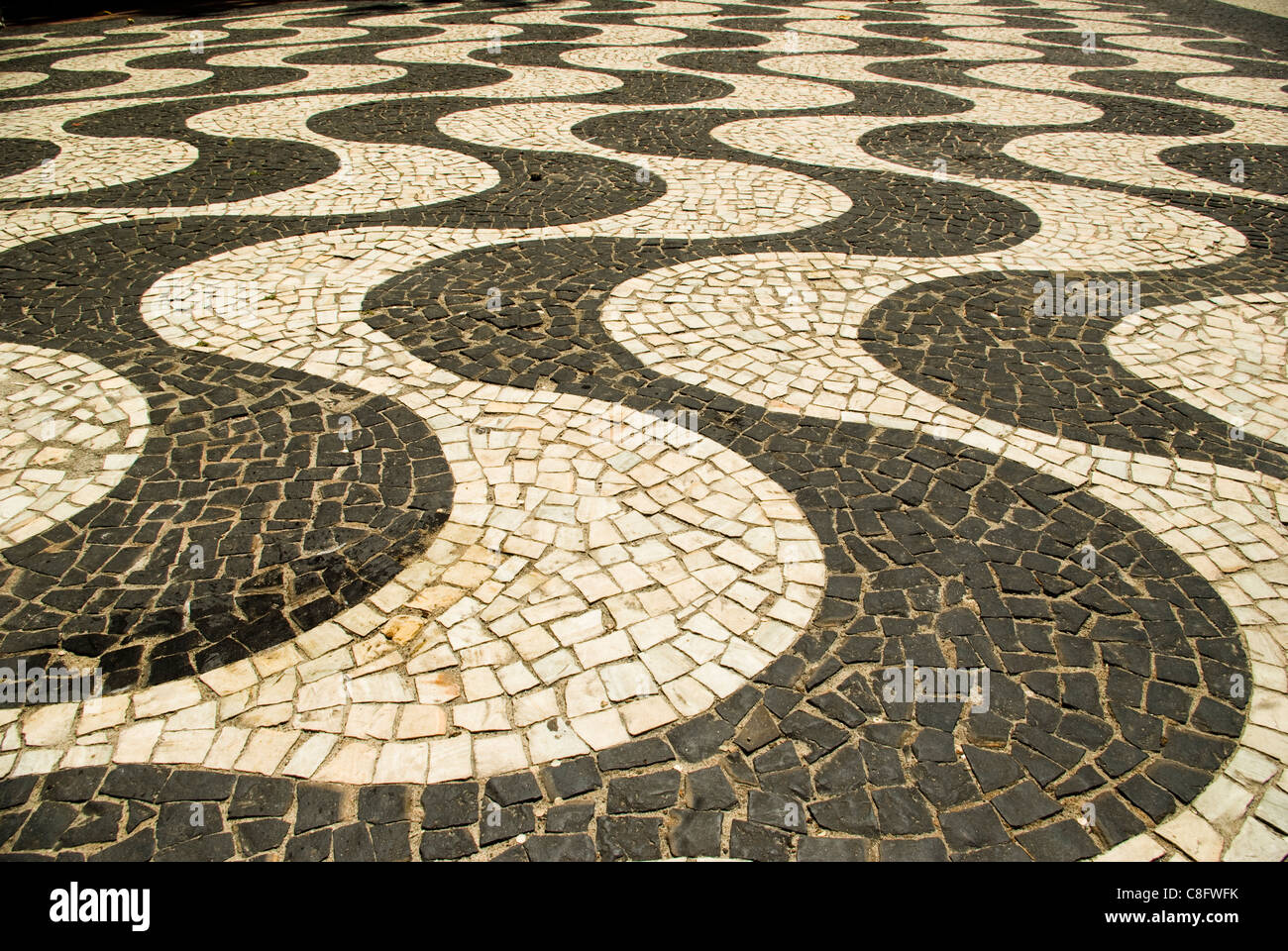 Black and white mosaic tiles form curving patterns on Copacobana sidewalks.. Rio de Janiero, Brazil Stock Photo