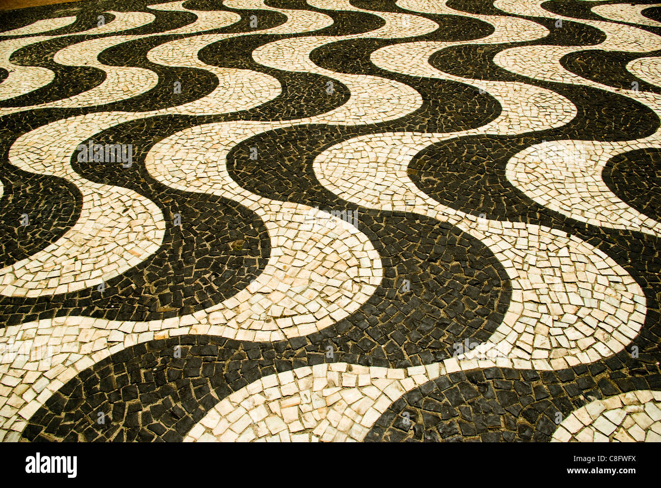 Black and white mosaic tiles form curving patterns on Copacobana sidewalks. Rio de Janiero, Brazil Stock Photo