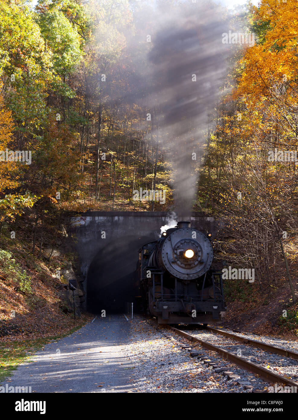 Old steam train pulling out of a tunnel belching steam and smoke Stock Photo