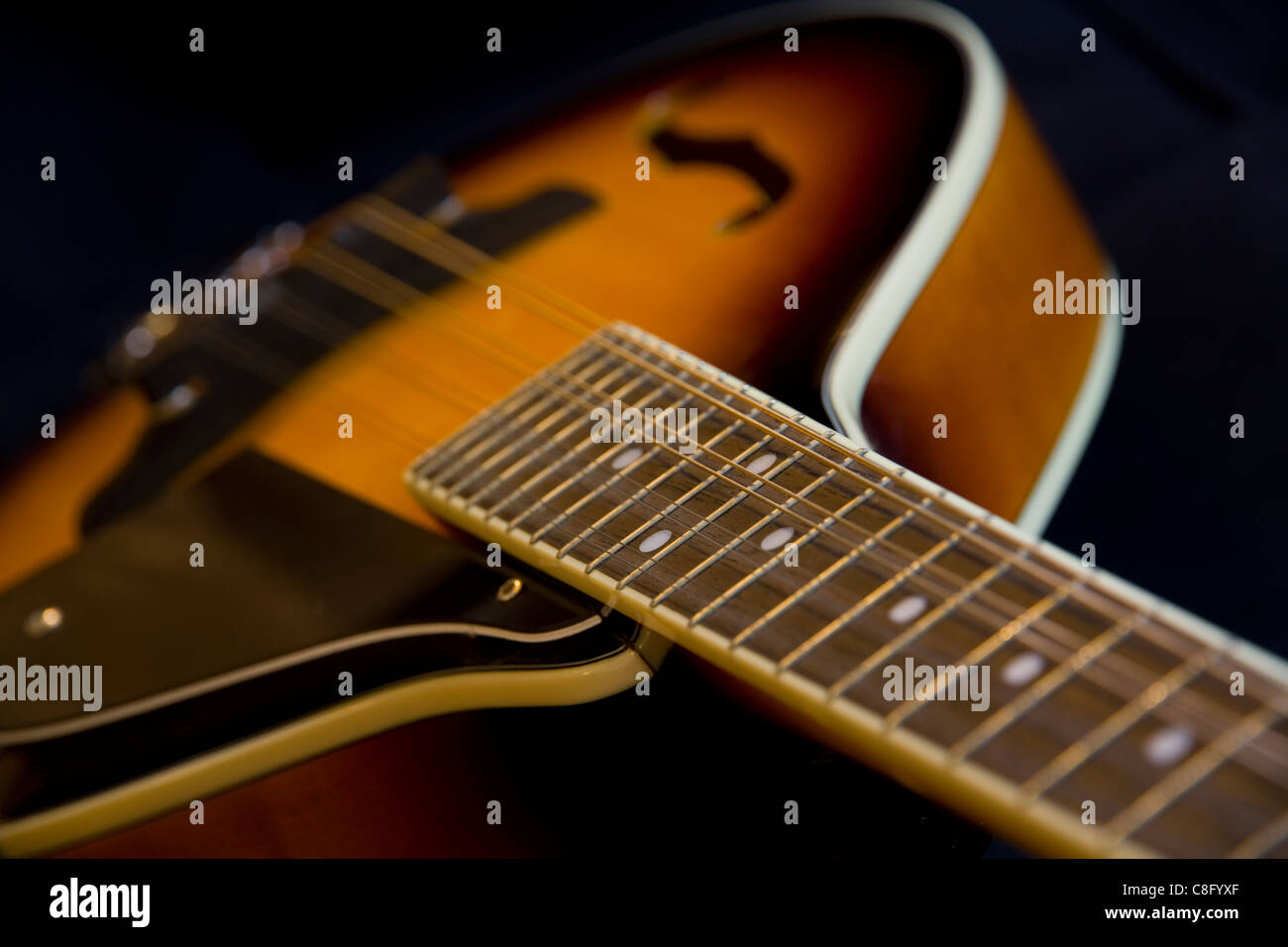 A close-up abstract of an A-frame Washburn mandolin fretboard on a black background Stock Photo