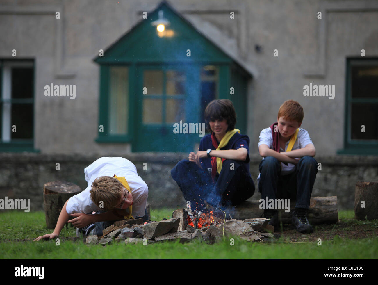 A scout blow onto a wood fire as they prepare a campfire during a scout outing Stock Photo