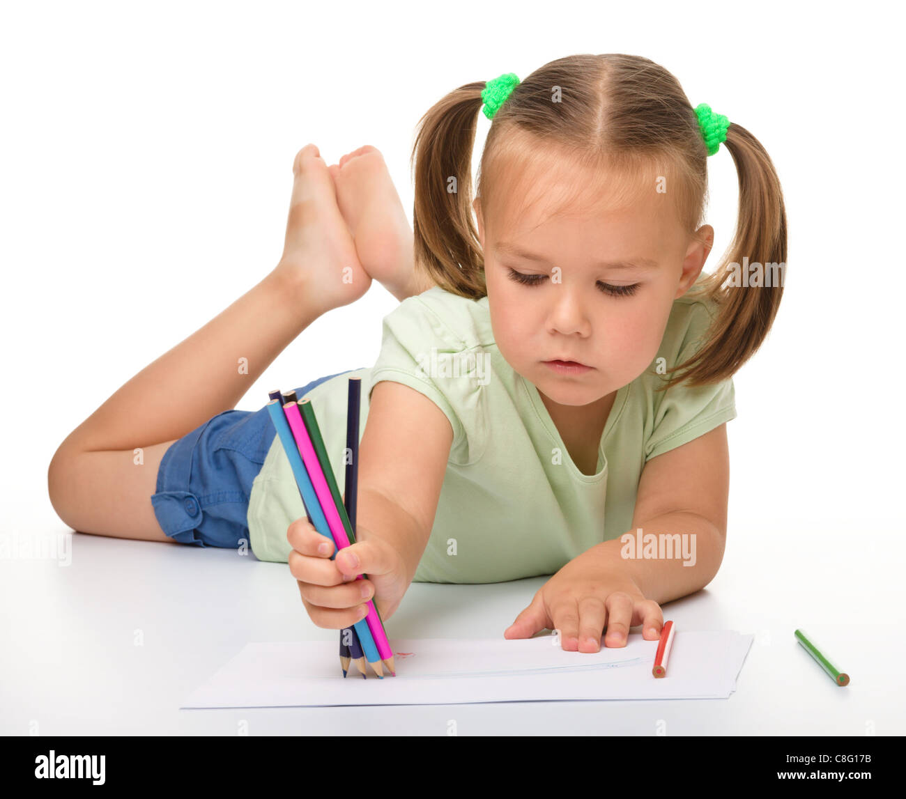 Cute little girl is drawing while laying on the floor, isolated over