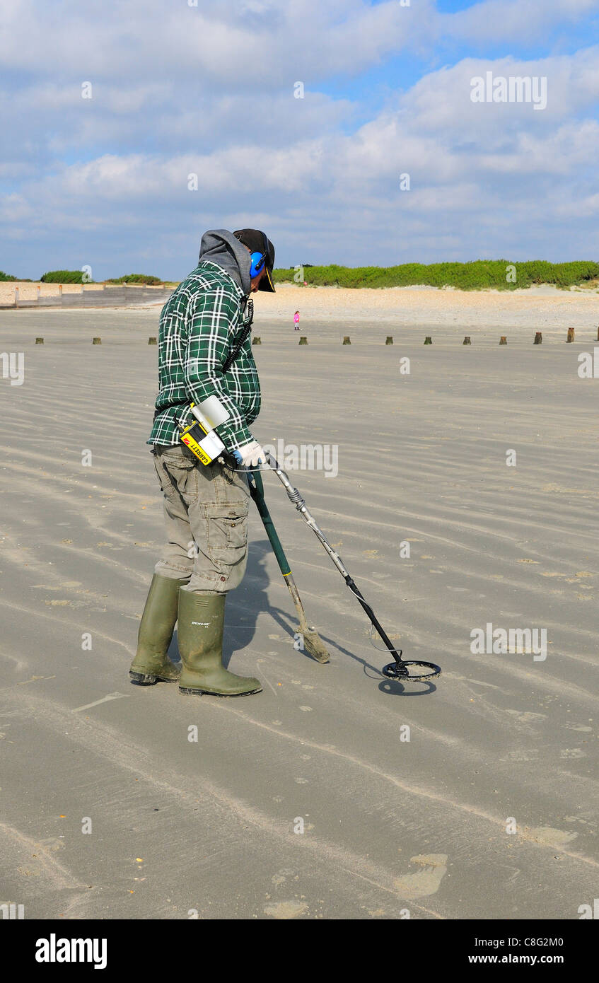 Man with metal detector looking for lost valuables on West Wittering beach after the weekends