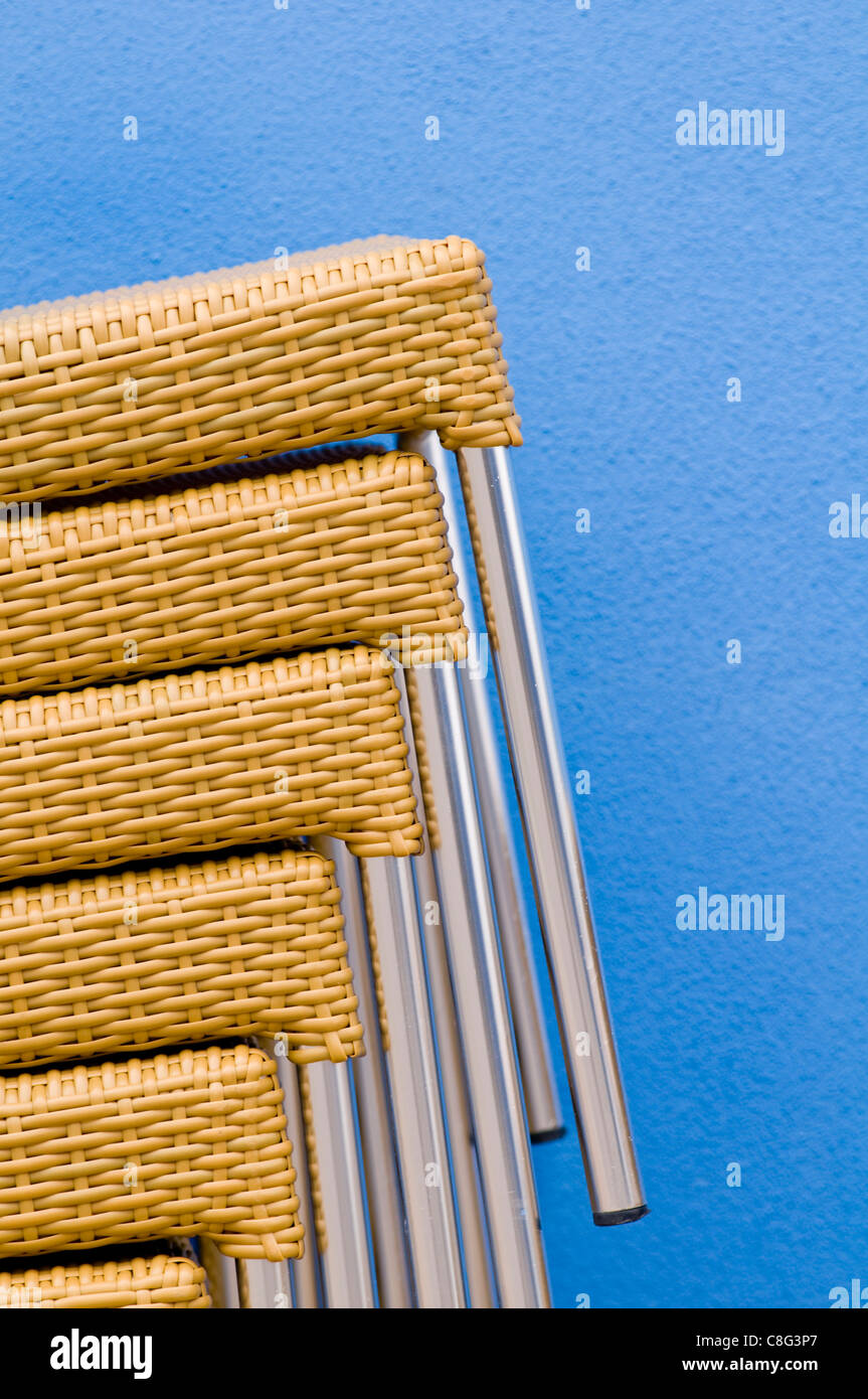 Chairs stacked against the exterior blue wall of a restaurant in the