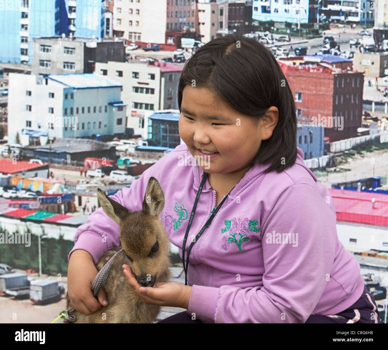 A Mongolian girl poses with a cuddly animal in front of a picture of ...