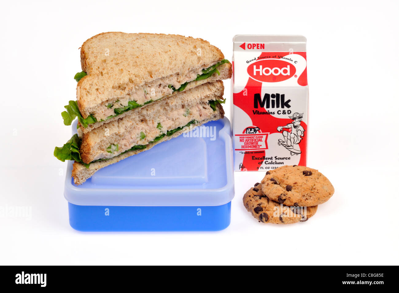 Tuna mayo with lettuce sandwich on wholemeal bread cut in half on lunch box with milk container and cookies  on white background, cutout. Stock Photo