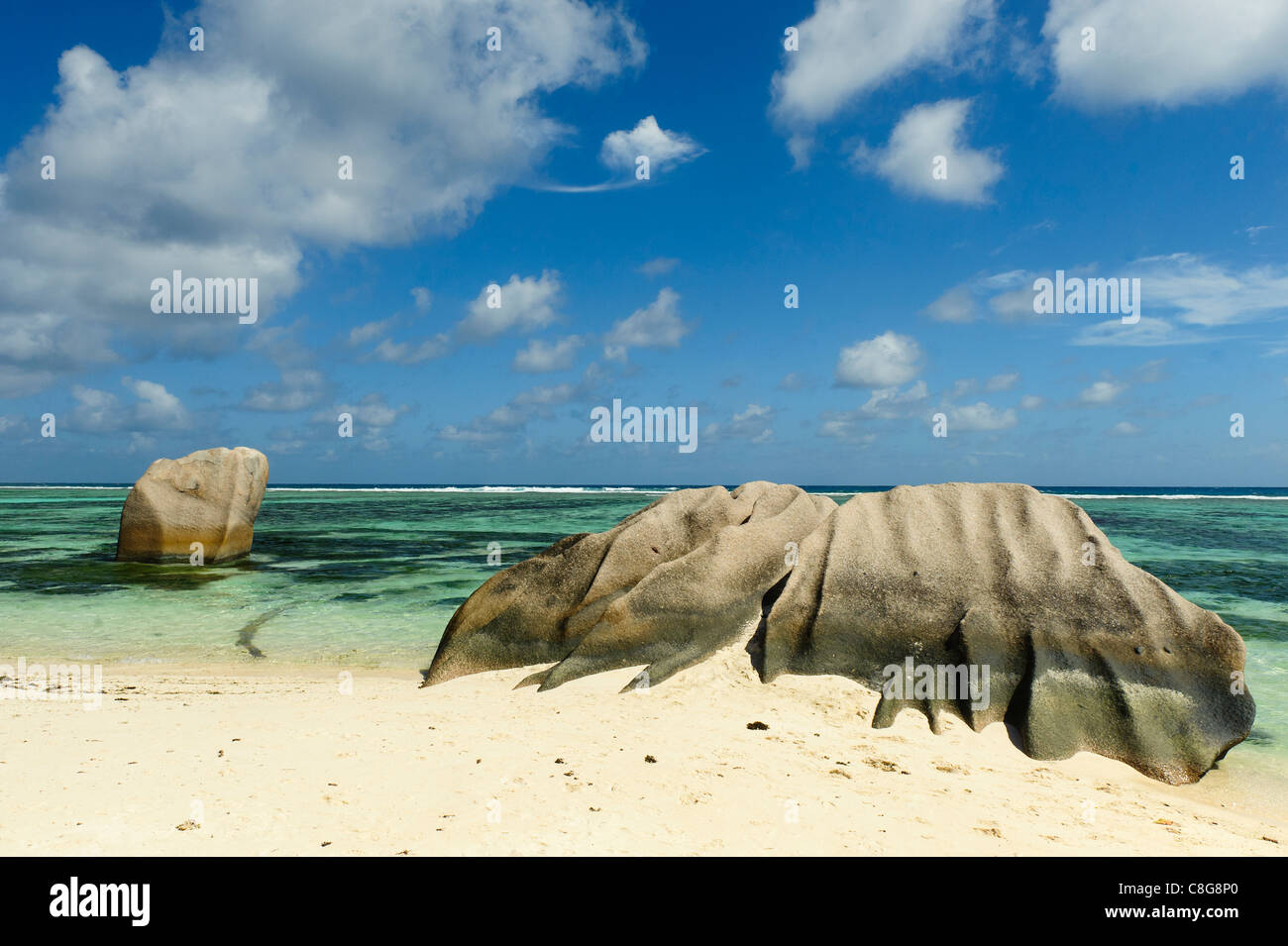 two granite boulders on secluded stretch of tropical beach rippled with pale sand and crystal clear turquoise  water Stock Photo