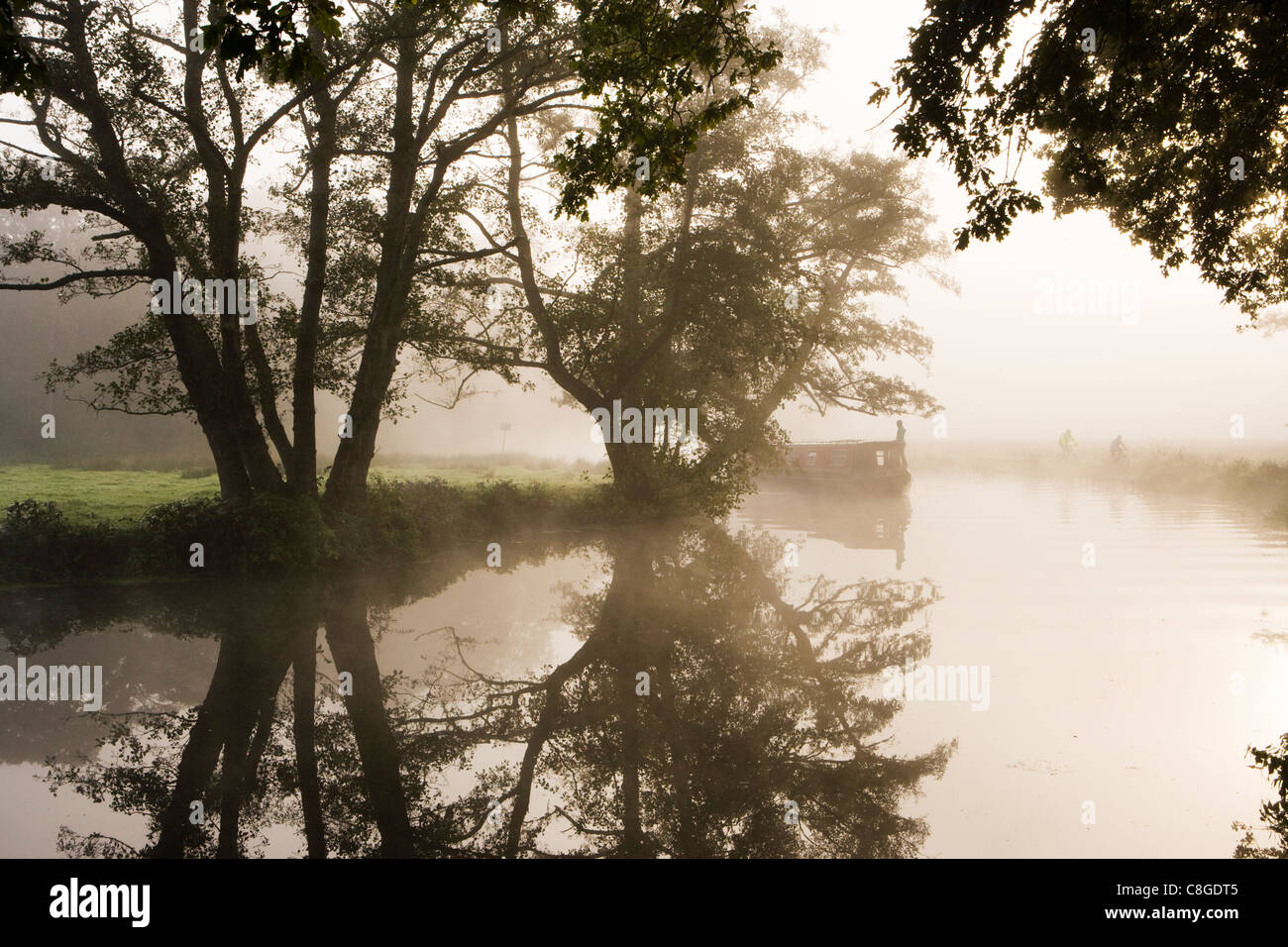 Misty dawn, boat and cyclists, River Wey at Pyrford, Surrey, UK. Stock Photo