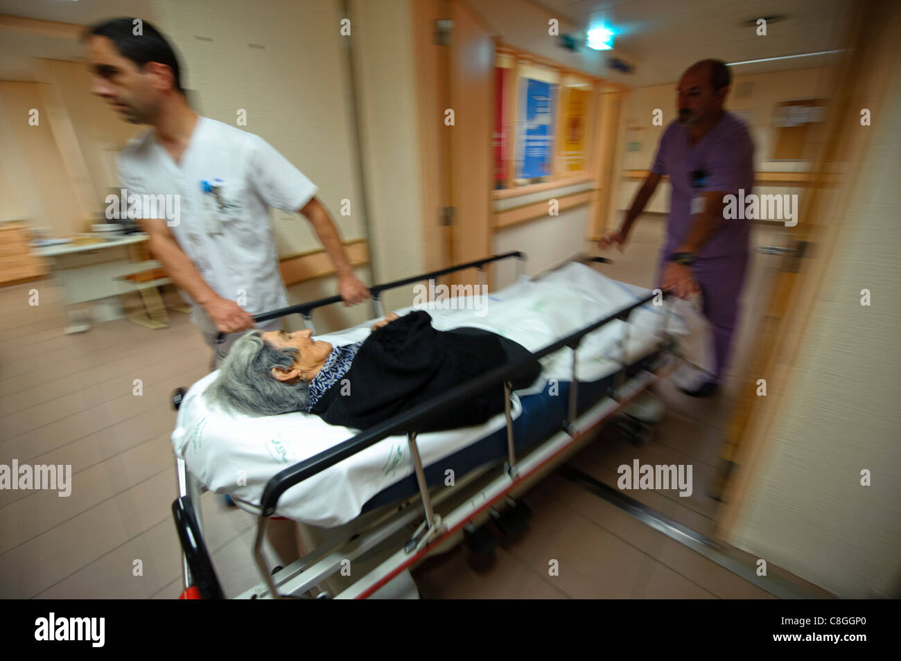 Motion blurred dynamic photo of healthcare professionals moving an old woman on a gurney in an hospital Stock Photo