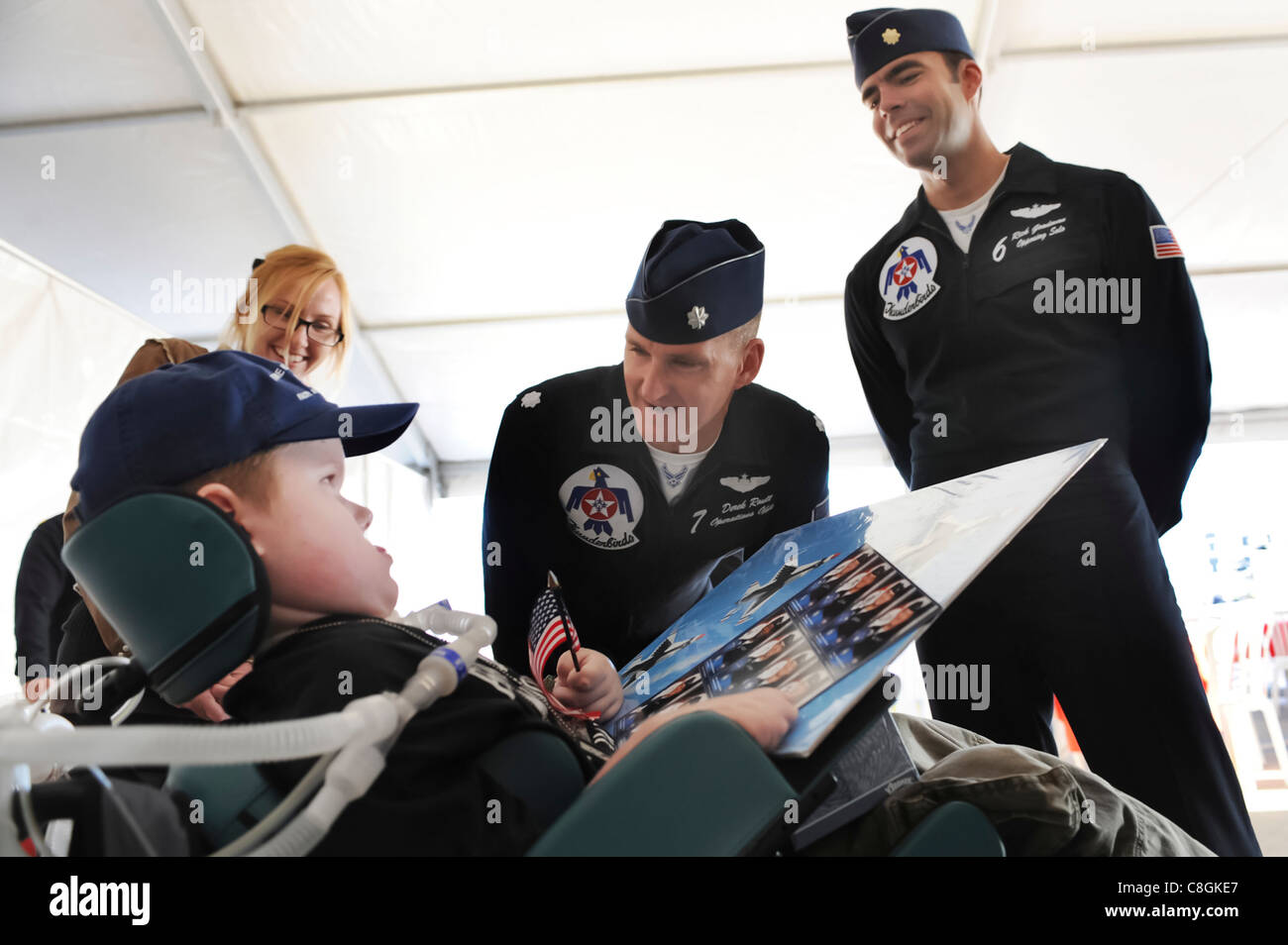 att Dembik Jr., a nine-year-old diagnosed with spinal muscular atrophy, gets an autograph from Thunderbirds operations officer Lt. Col. Derek Routt and solo pilot Maj. Rick Goodman during the rehearsal show for the Nellis Air Force Base, Nev., Open House Nov. 13, 2009. Matt was invited to attend the rehearsal through the Make-a-Wish Foundation, a non-profit organization aimed toward granting wishes of children with life-threatening conditions. Stock Photo