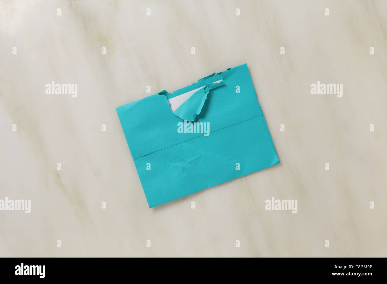 A used and slightly torn open postal envelope on a marble surface Bright teal blue colored envelope Stock Photo