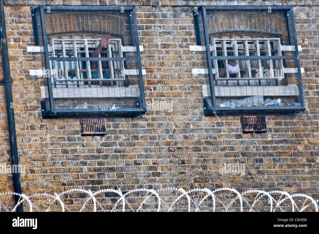 Prisoners waving out their cell window in Brixton prison in South London Stock Photo