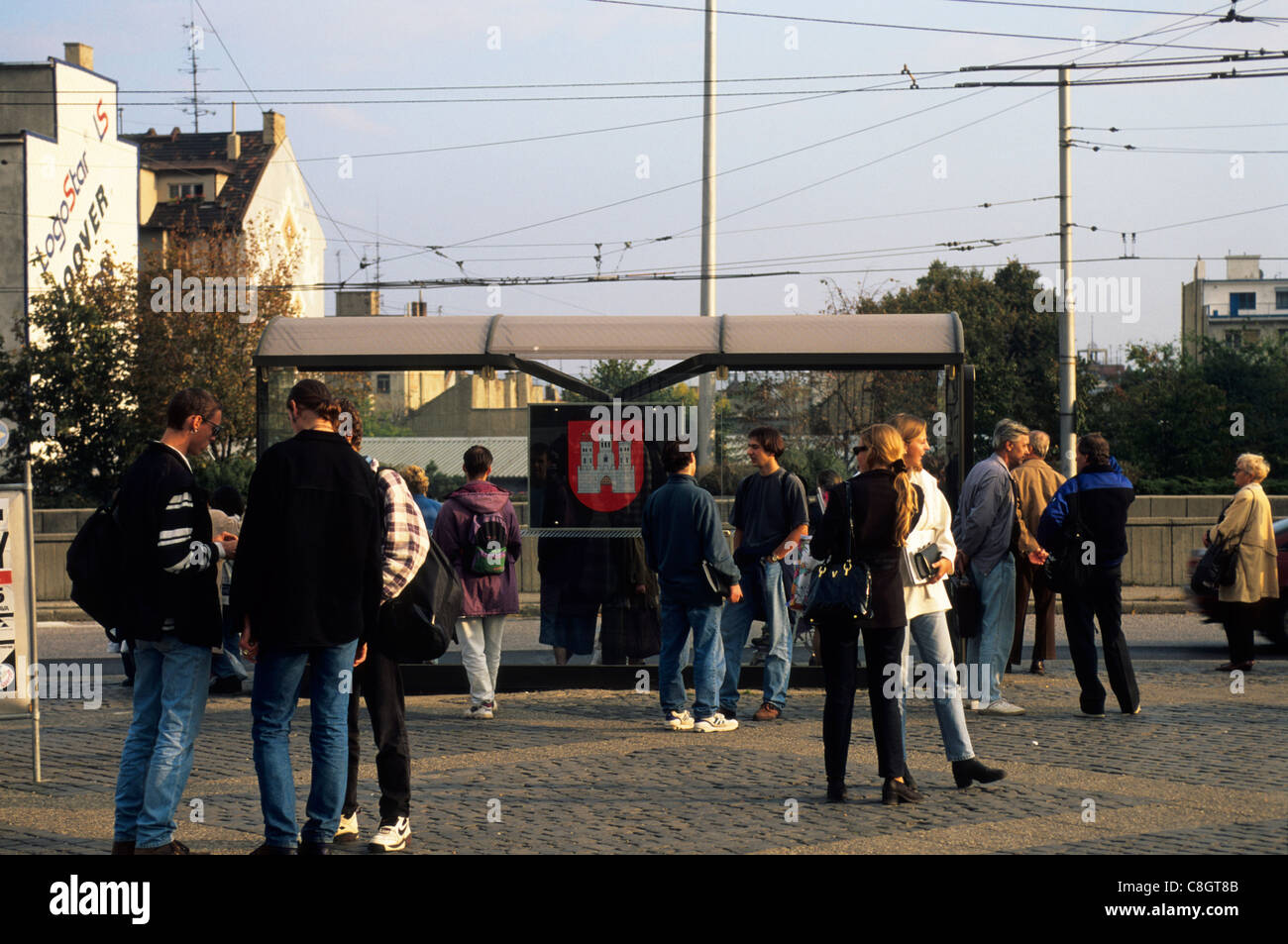 Bratislava, Slovakia: people at a trolley bus stop with the three tower castle motif of the city. Stock Photo