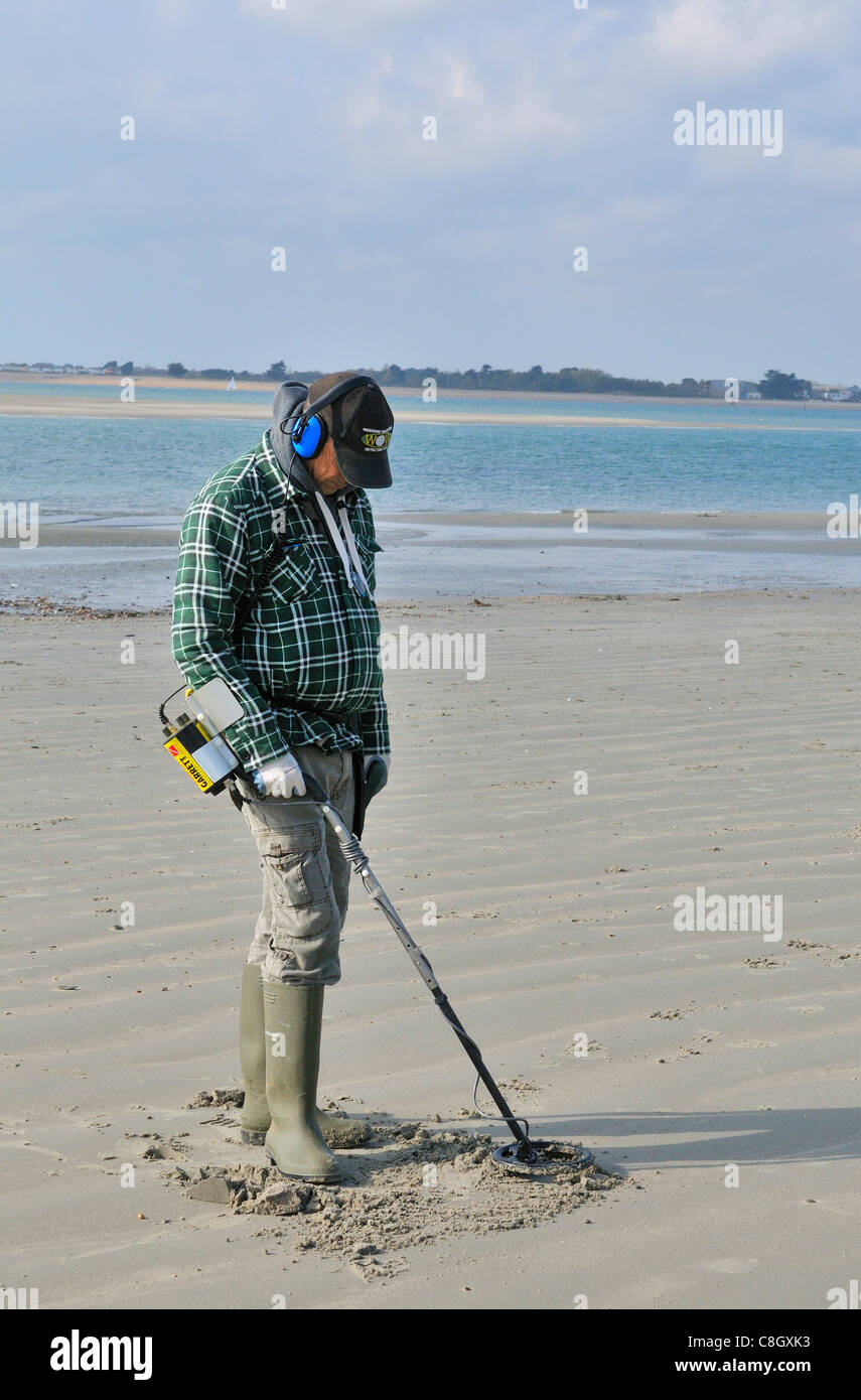 Man with metal detector looking for lost valuables on West Wittering beach after the weekends