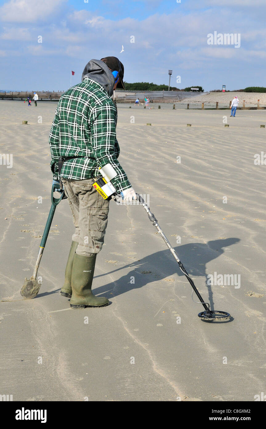 Man with metal detector looking for lost valuables on West Wittering beach after the weekends