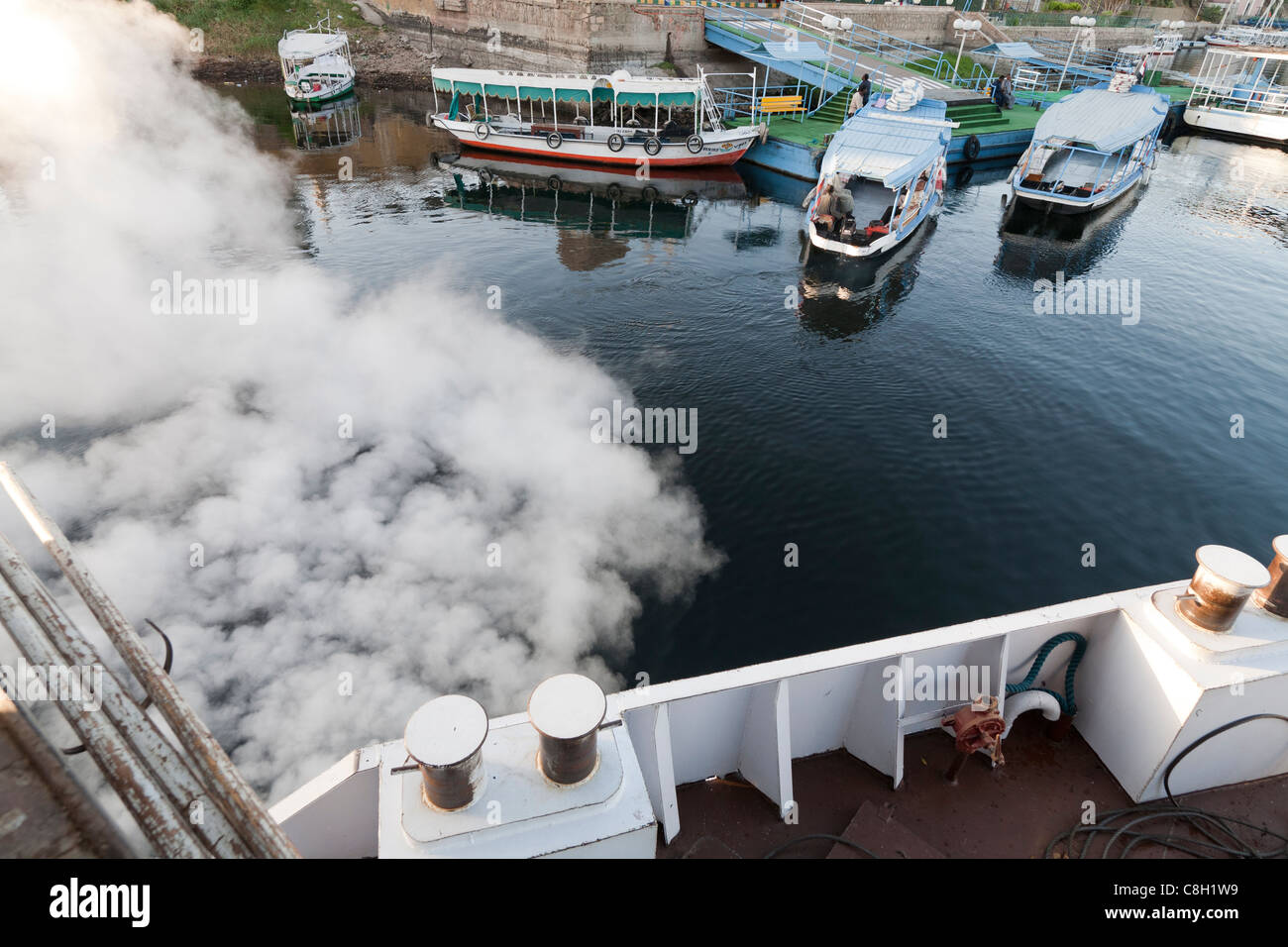 Looking down on the deck of a ship as it vents steam leaving harbour with water taxis in the distance, river Nile, Egypt Stock Photo