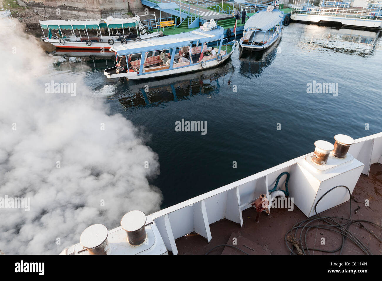 Looking down on the deck of a ship as it vents steam leaving harbour with water taxis in the distance, river Nile, Egypt Stock Photo