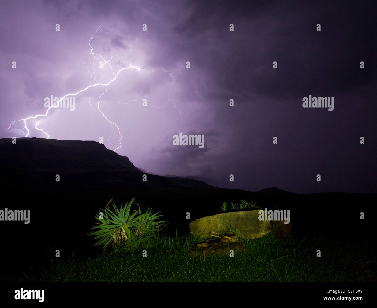 Lightning illuminates purple sky over Drakensberg Mountains Stock Photo
