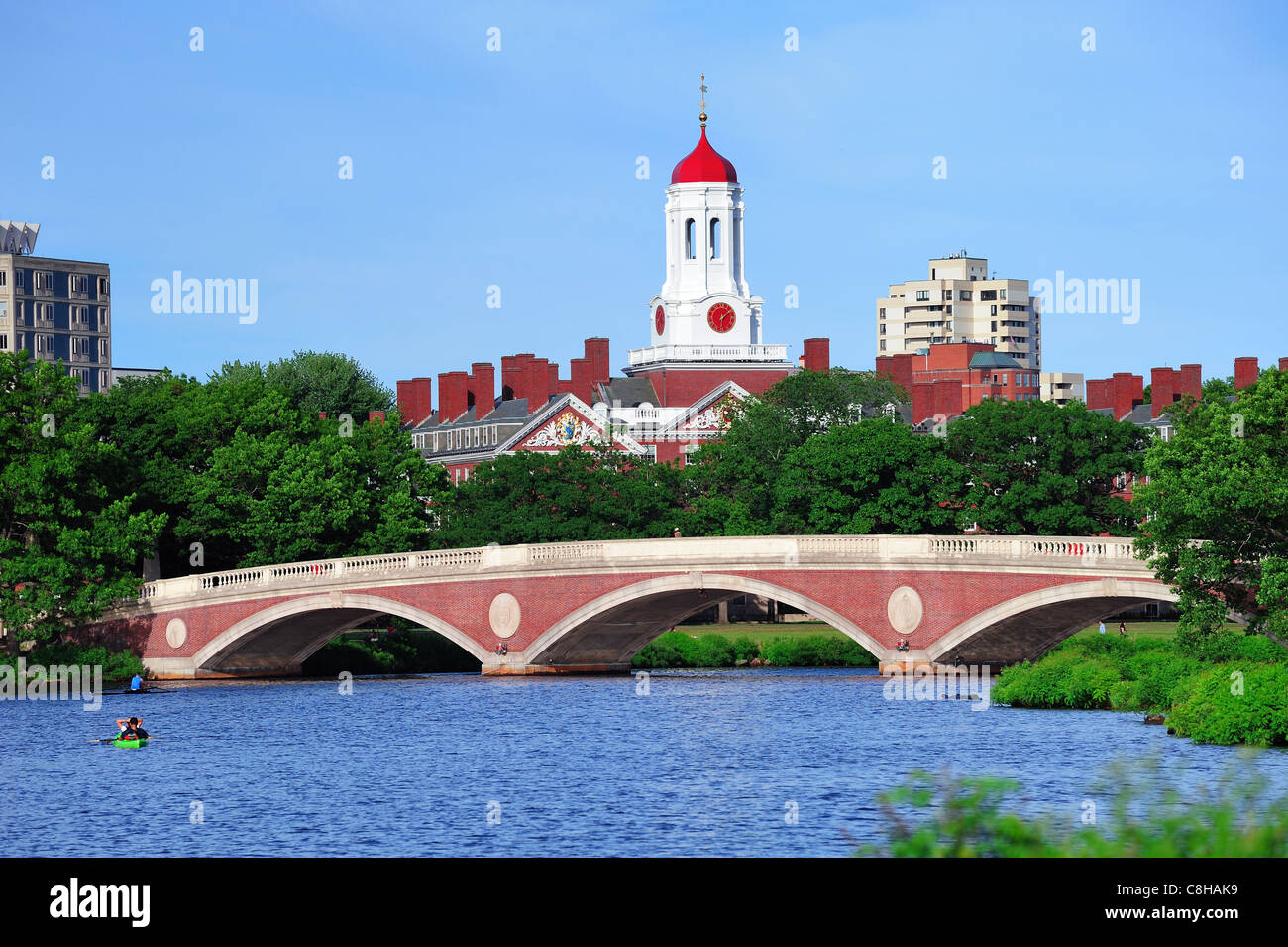 John W. Weeks Bridge and clock tower over Charles River in Harvard University campus in Boston with trees, boat and blue sky. Stock Photo