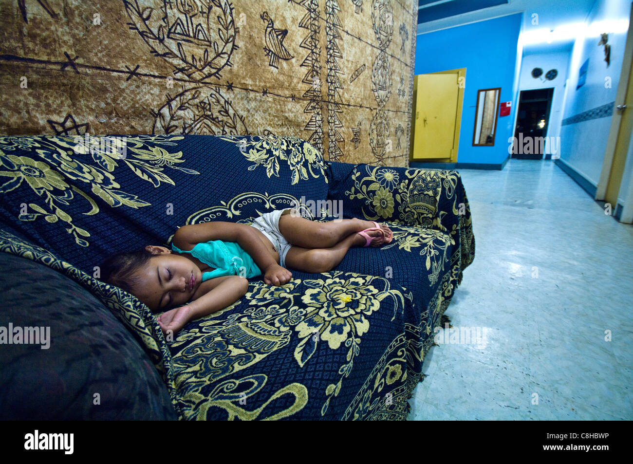 A small girl sleeps on a couch in the foyer of a backpackers' lodge. Stock Photo