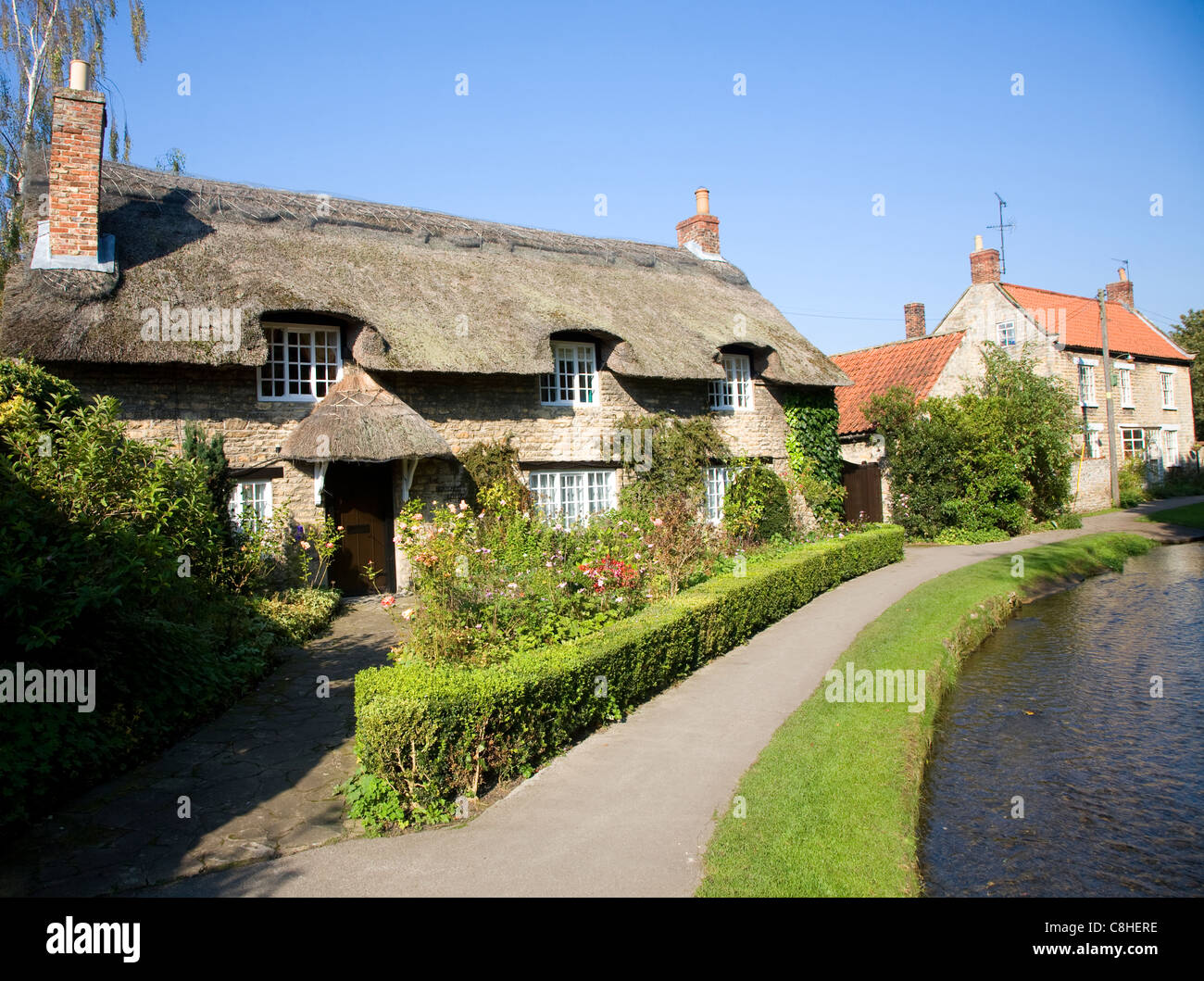 Thatched cottage by stream, Thornton le Dale, Yorkshire, England Stock Photo