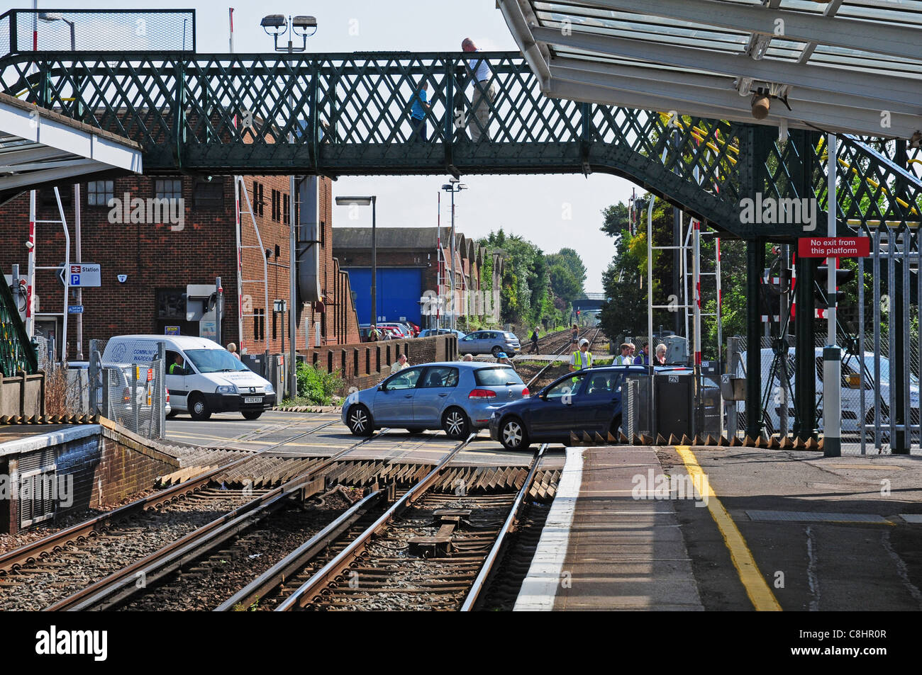 Cars and people crossing level crossing after train has pulled into Chichester Station Stock Photo
