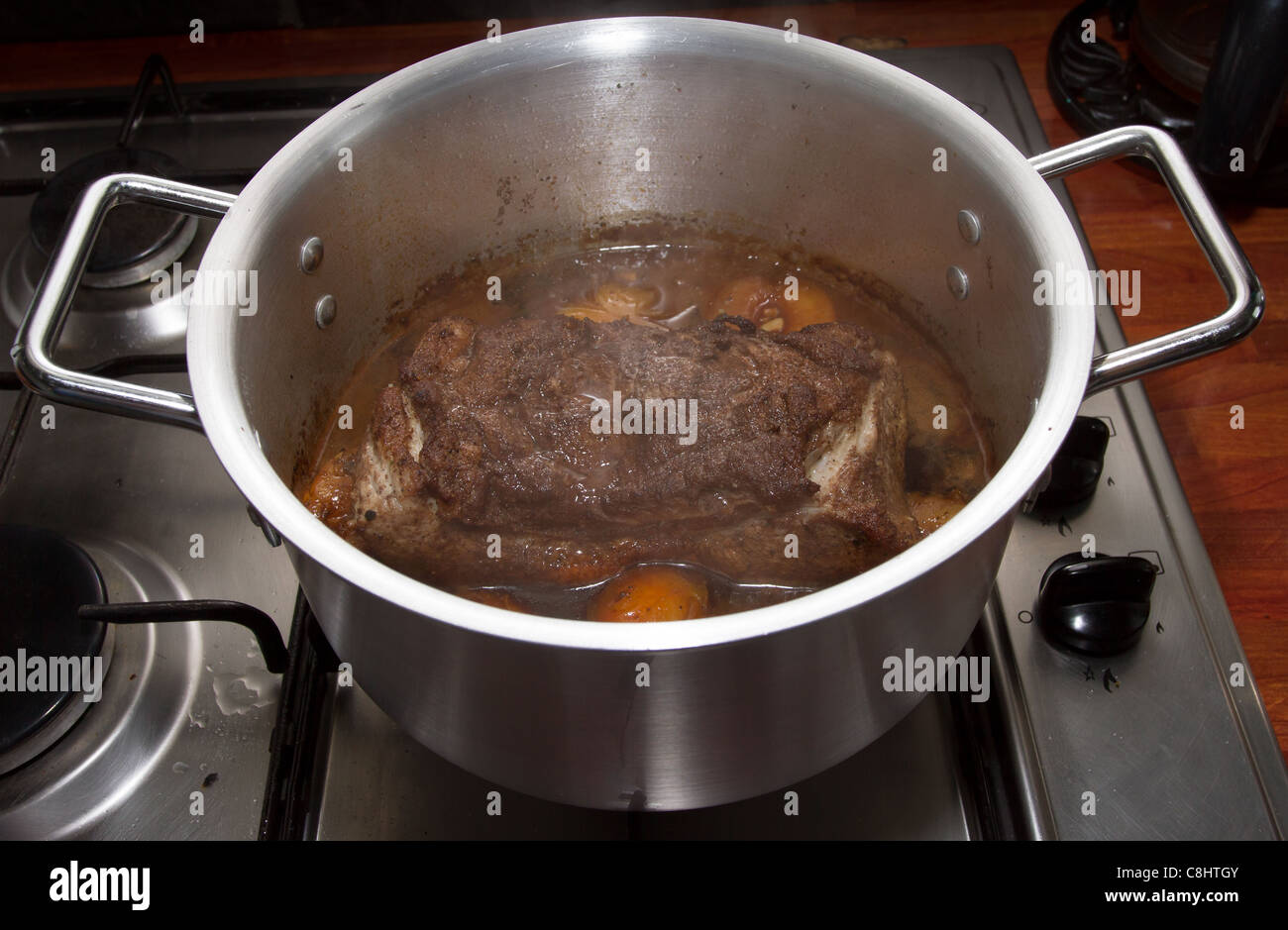 Asian spiced pork with plums simmering in silver cooking pot. Stock Photo